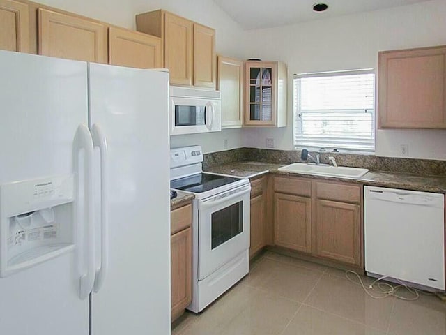 kitchen with dark countertops, white appliances, light tile patterned flooring, and a sink