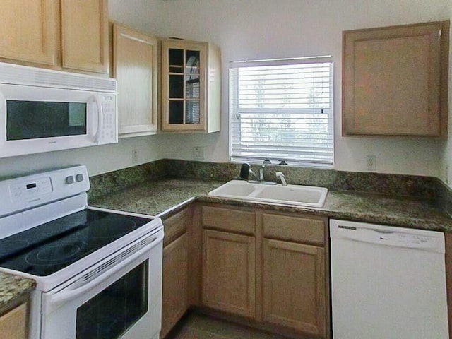 kitchen with a sink, glass insert cabinets, white appliances, and dark countertops