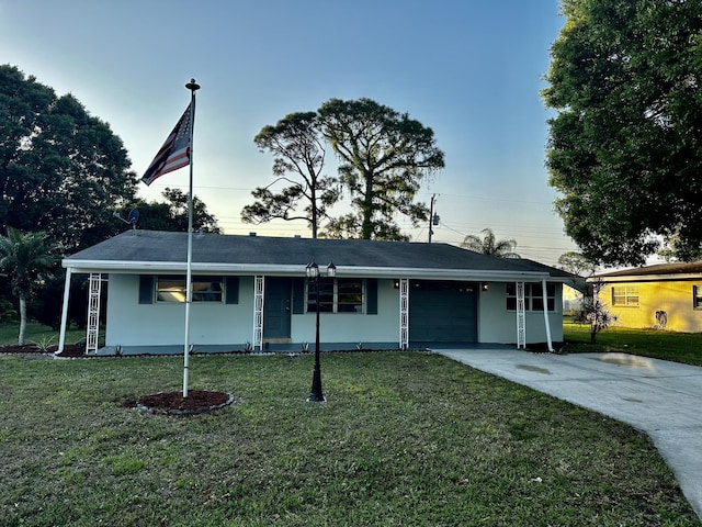 single story home featuring a front lawn, an attached garage, driveway, and stucco siding