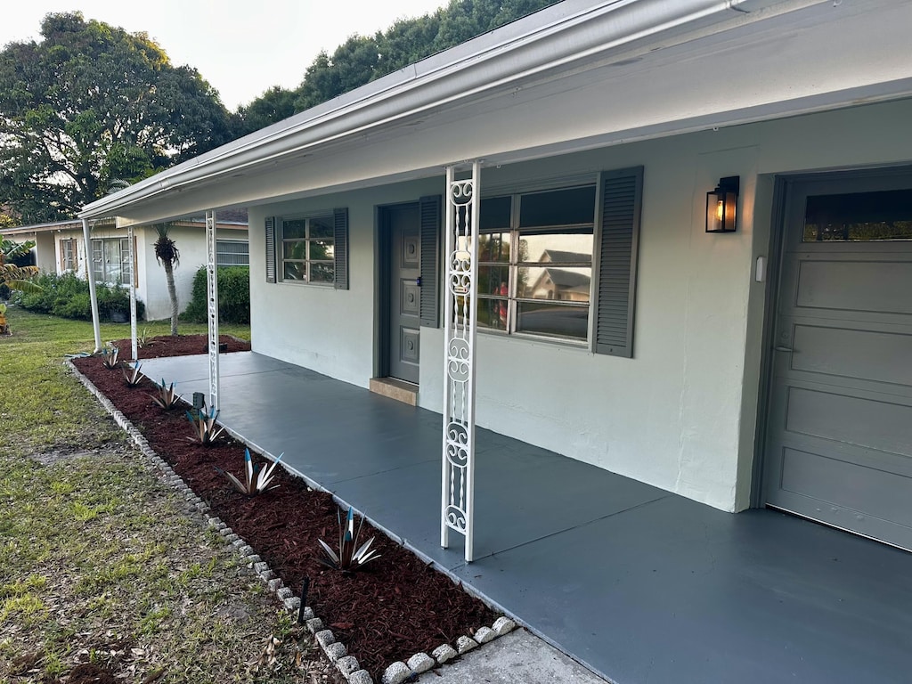 property entrance with covered porch and stucco siding