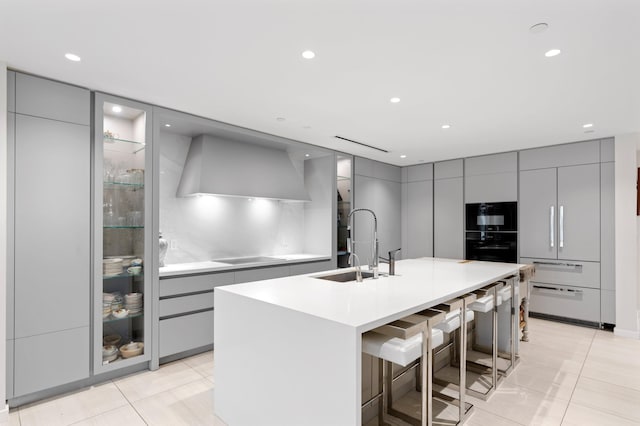 kitchen featuring light tile patterned floors, gray cabinets, modern cabinets, and wall chimney range hood