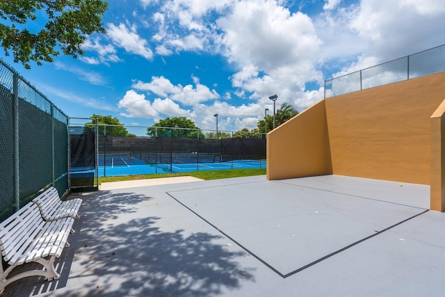 exterior space featuring a tennis court and fence