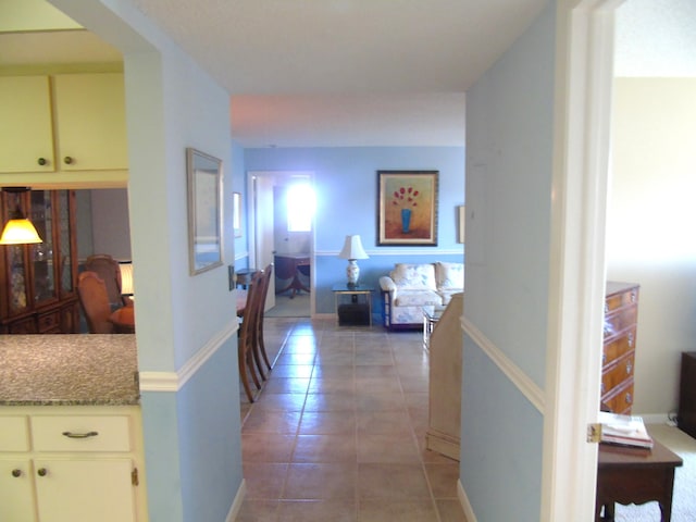 hall featuring light tile patterned floors and baseboards