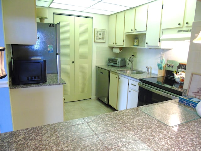 kitchen with under cabinet range hood, a sink, backsplash, appliances with stainless steel finishes, and light tile patterned flooring