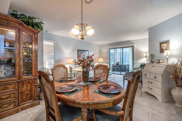 dining area featuring light tile patterned floors, a notable chandelier, and a textured ceiling