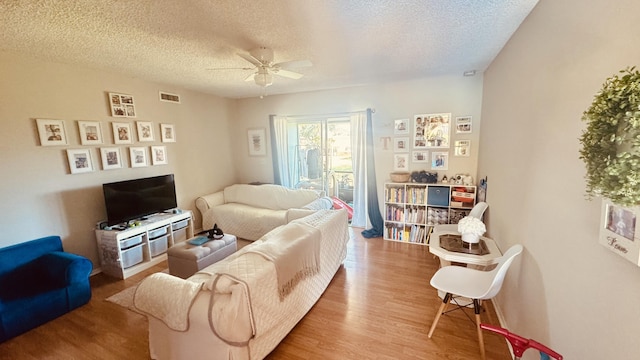 living room with visible vents, a textured ceiling, ceiling fan, and wood finished floors