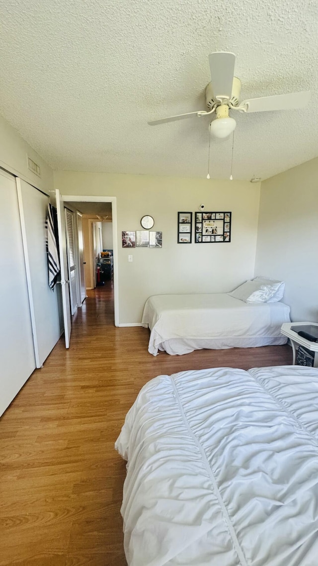 bedroom featuring a closet, a textured ceiling, wood finished floors, and a ceiling fan