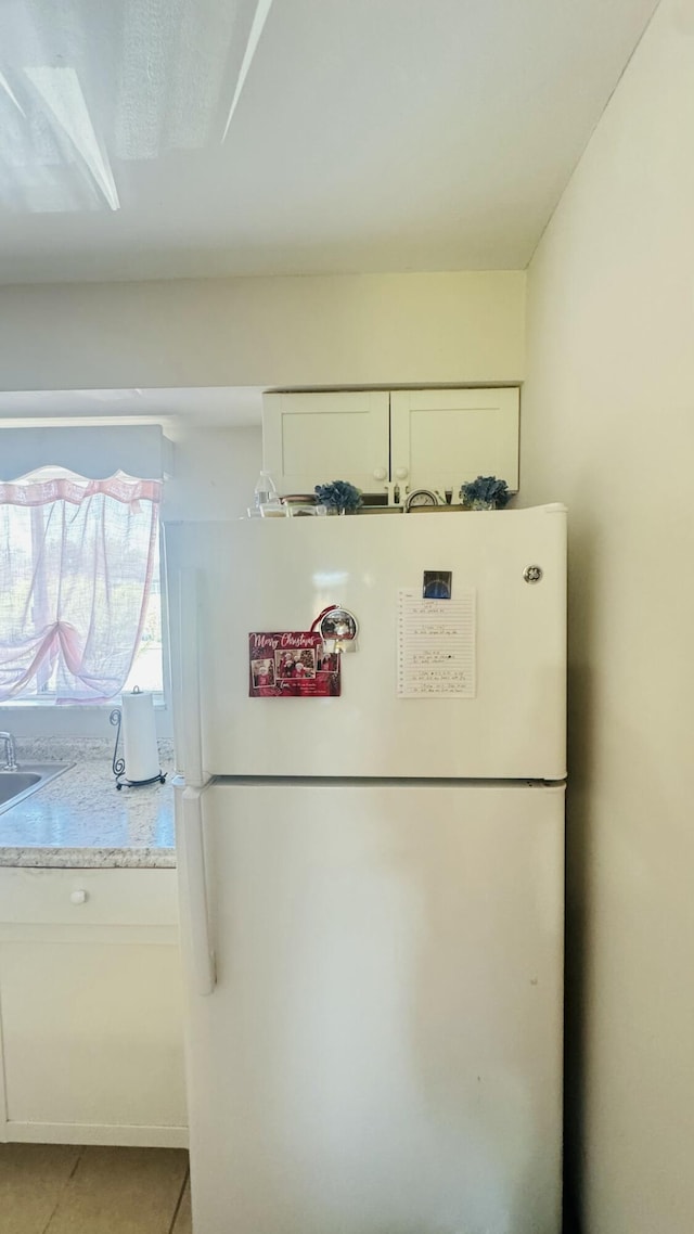 details with white cabinetry, light countertops, and freestanding refrigerator