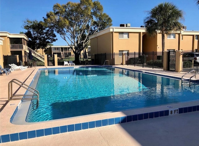 community pool with a patio and fence