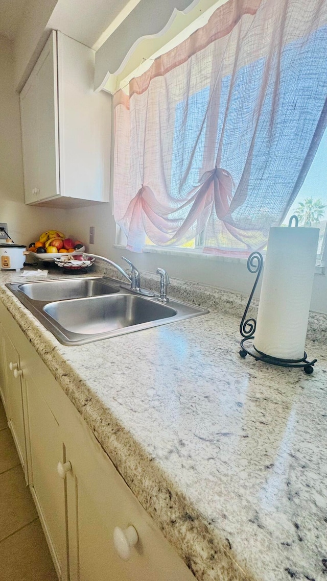 kitchen with a sink, plenty of natural light, white cabinets, and light countertops