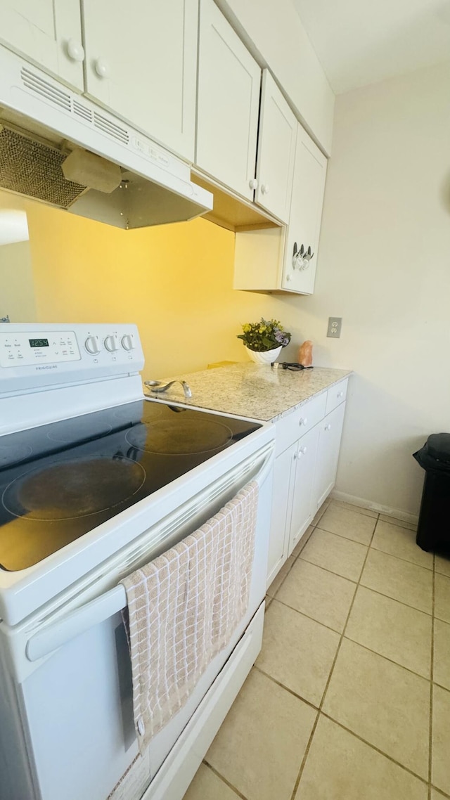 kitchen with under cabinet range hood, white range with electric stovetop, white cabinets, light countertops, and light tile patterned floors