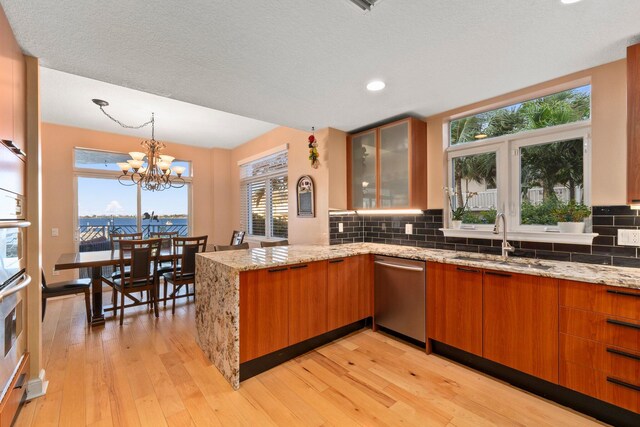 309 E Ocean Ave Unit 103, Lantana, FL 33462 - kitchen featuring brown cabinetry, decorative backsplash, a sink, and a peninsula