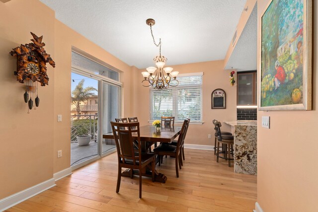 309 E Ocean Ave Unit 103, Lantana, FL 33462 - dining room featuring baseboards, a textured ceiling, light wood-style flooring, and an inviting chandelier