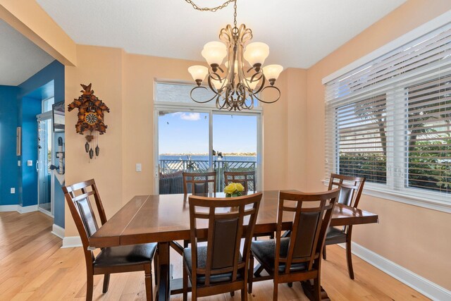 309 E Ocean Ave Unit 103, Lantana, FL 33462 - dining space with a notable chandelier, baseboards, light wood finished floors, and a wealth of natural light