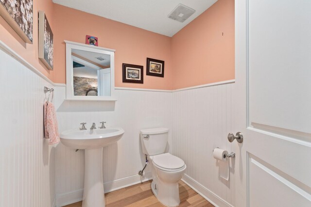 309 E Ocean Ave Unit 103, Lantana, FL 33462 - half bathroom with toilet, a wainscoted wall, visible vents, and wood finished floors