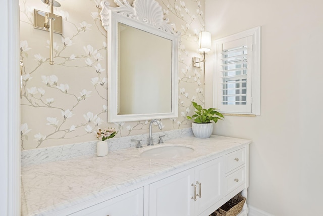 bathroom featuring wallpapered walls, vanity, and baseboards