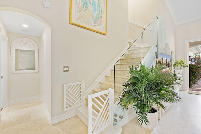 staircase featuring arched walkways, crown molding, and baseboards