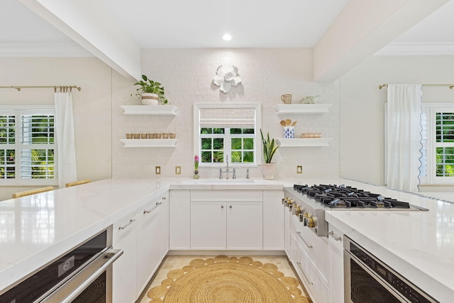 kitchen with open shelves, a healthy amount of sunlight, a sink, and stainless steel gas cooktop