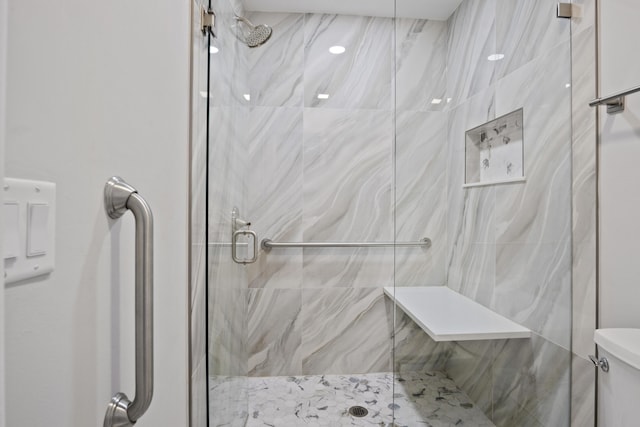 bathroom featuring a marble finish shower and toilet