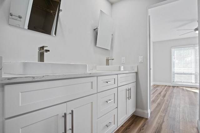 bathroom with double vanity, wood finished floors, ceiling fan, and a sink