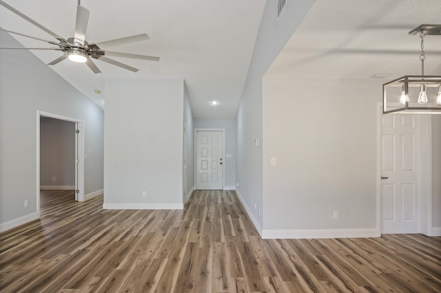 interior space featuring visible vents, wood finished floors, baseboards, and vaulted ceiling