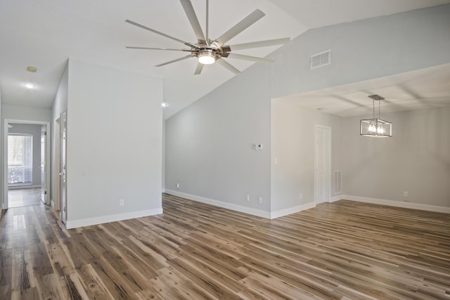 spare room featuring visible vents, lofted ceiling, wood finished floors, and ceiling fan with notable chandelier