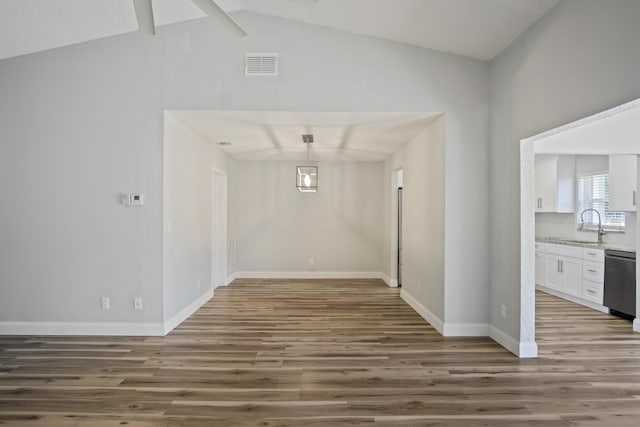 unfurnished dining area featuring visible vents, a sink, wood finished floors, baseboards, and vaulted ceiling