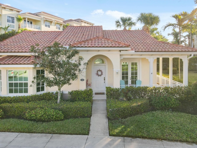 mediterranean / spanish house with a tiled roof, french doors, and stucco siding