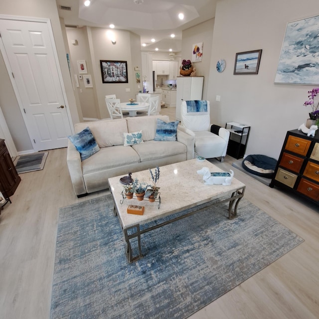 living area with light wood finished floors, visible vents, and recessed lighting