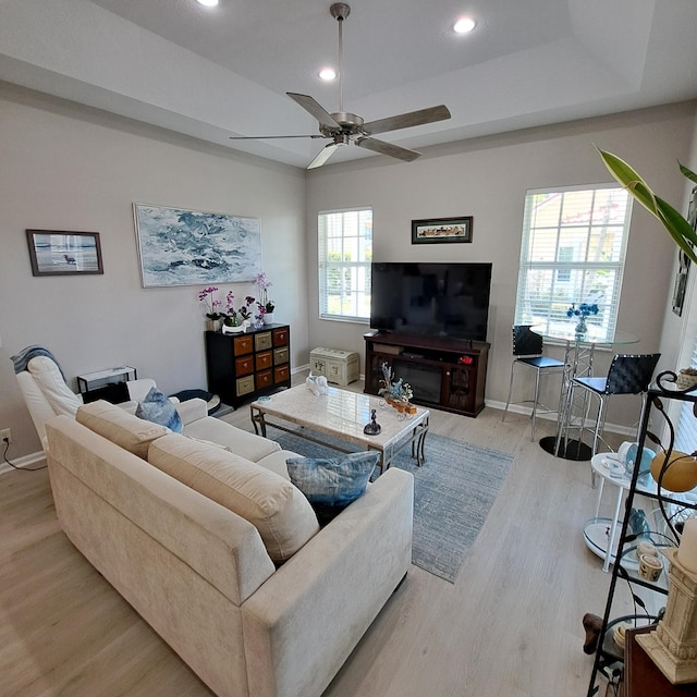 living room with a ceiling fan, wood finished floors, baseboards, recessed lighting, and a raised ceiling