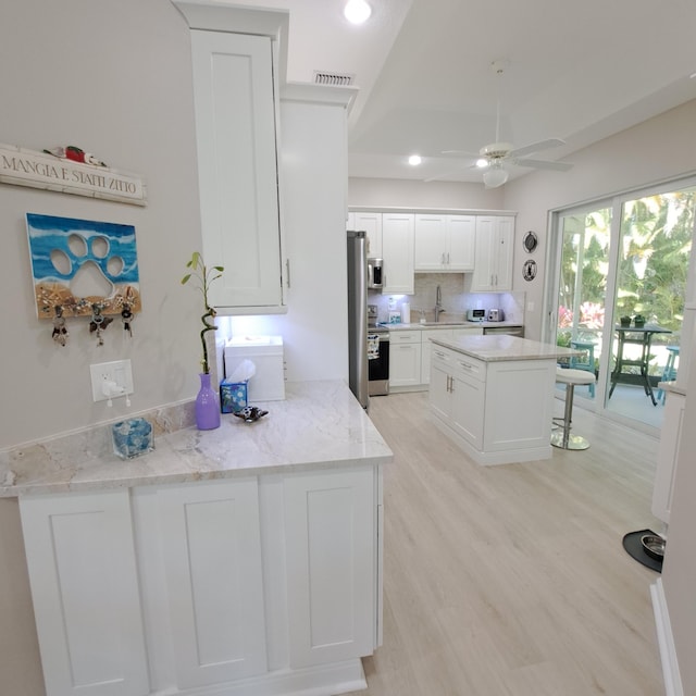 kitchen with light wood-type flooring, visible vents, a ceiling fan, white cabinetry, and stainless steel appliances