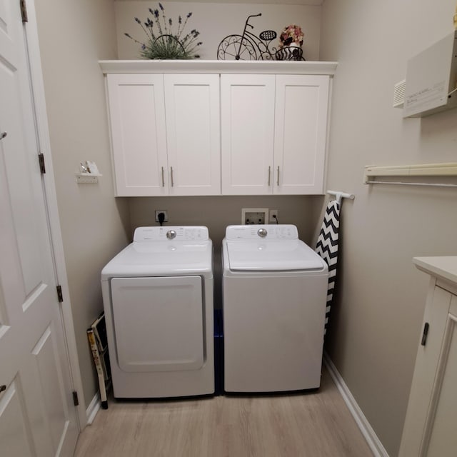 clothes washing area with cabinet space, independent washer and dryer, baseboards, and light wood-style floors