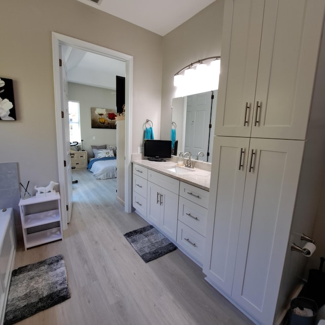 ensuite bathroom featuring vanity, ensuite bathroom, and wood finished floors