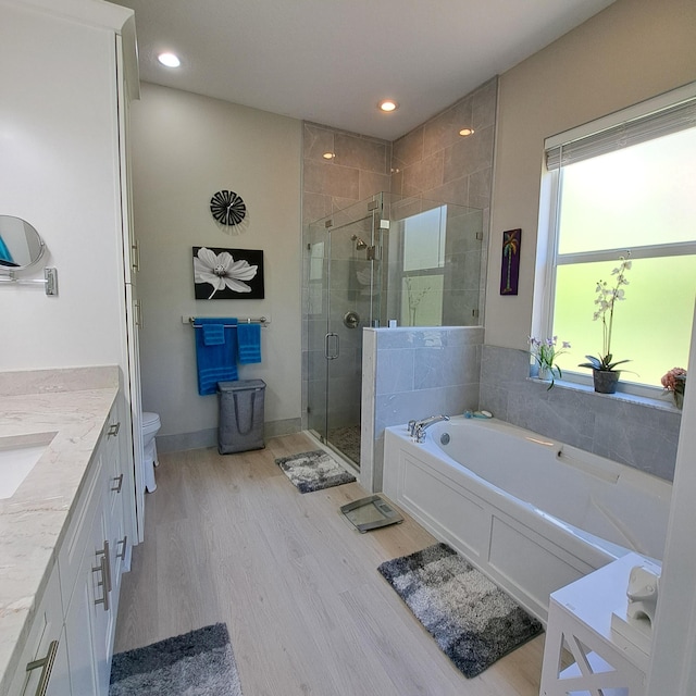 bathroom with toilet, a stall shower, wood finished floors, a bath, and vanity