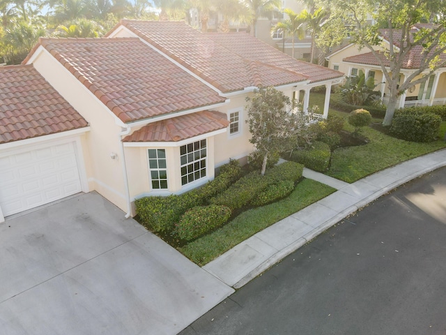 view of front of property with stucco siding, driveway, a tile roof, and an attached garage