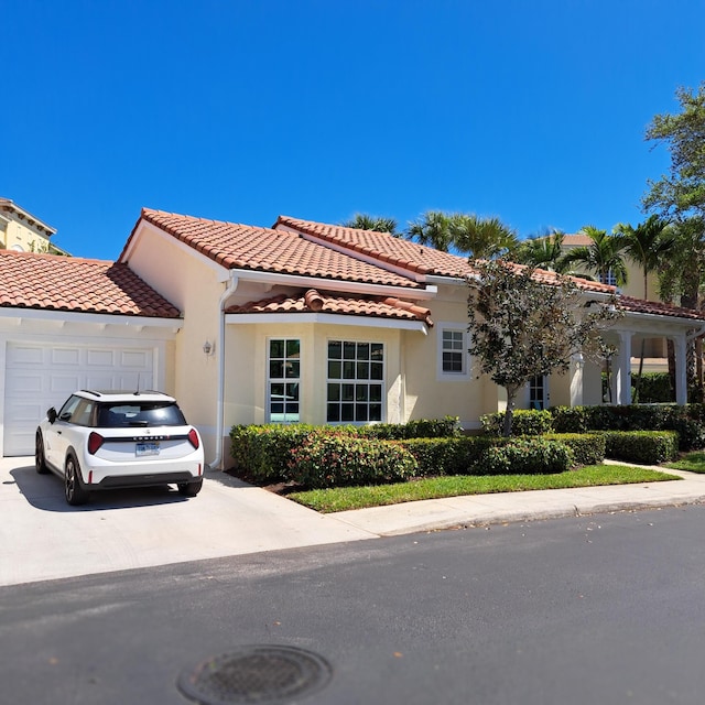 mediterranean / spanish-style home featuring a tiled roof, an attached garage, driveway, and stucco siding