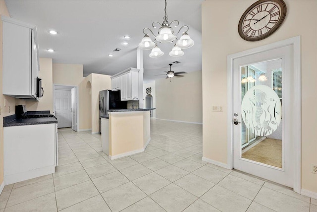 kitchen with ceiling fan with notable chandelier, a sink, dark countertops, white cabinetry, and light tile patterned floors