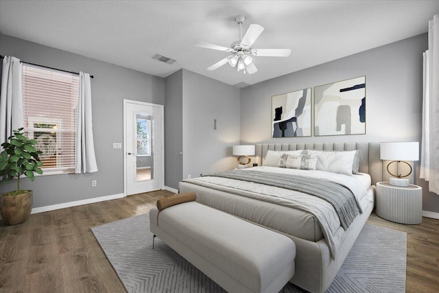 bedroom featuring ceiling fan, wood finished floors, visible vents, and baseboards