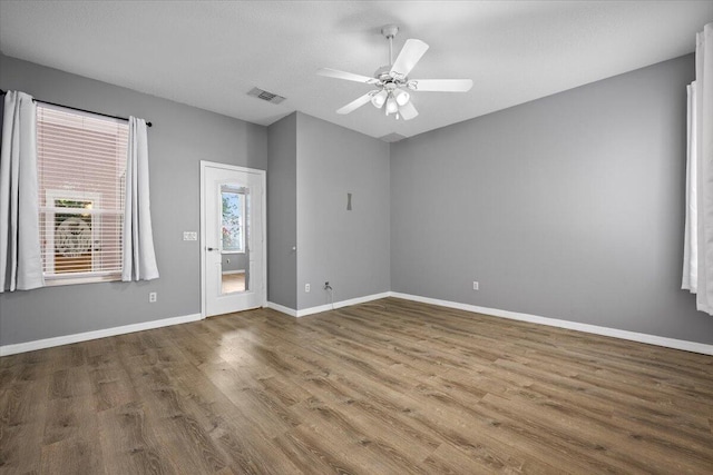 spare room featuring visible vents, baseboards, wood finished floors, and a ceiling fan