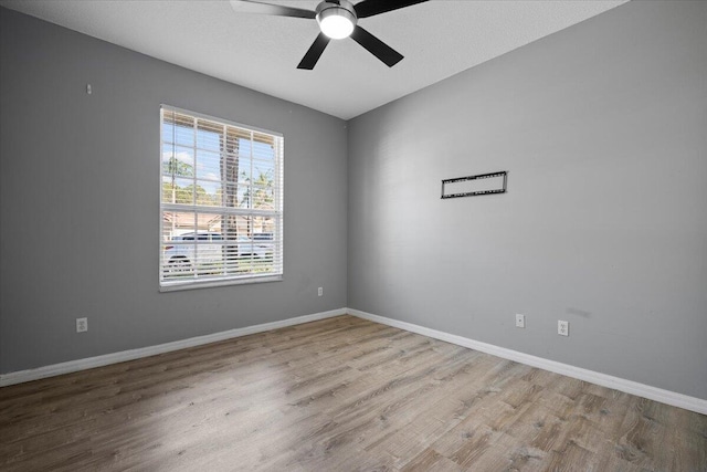 unfurnished room with baseboards, wood finished floors, and a ceiling fan