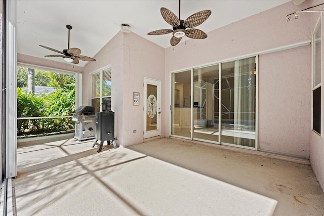 unfurnished sunroom with a ceiling fan and vaulted ceiling