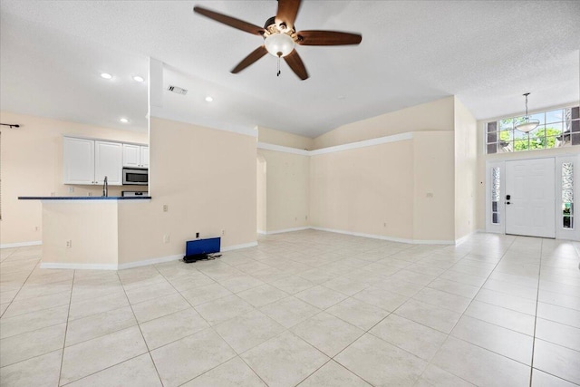 unfurnished living room with light tile patterned floors, a ceiling fan, visible vents, baseboards, and vaulted ceiling