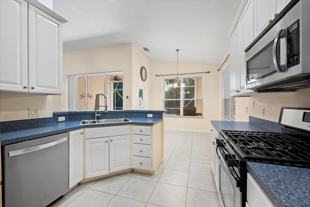 kitchen with a notable chandelier, a sink, dark countertops, stainless steel appliances, and a peninsula