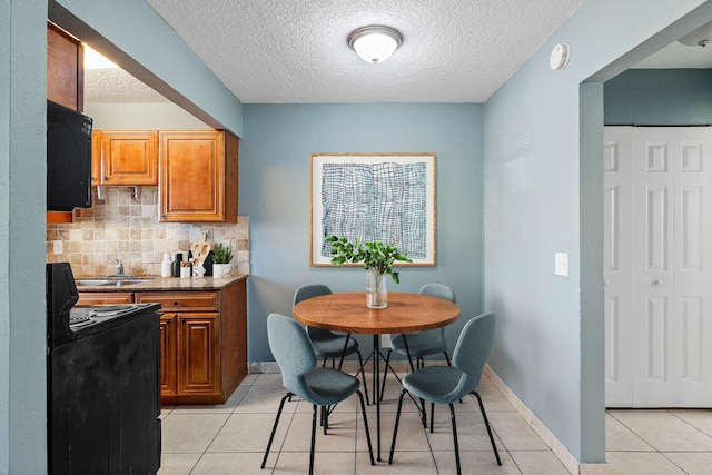 dining room featuring light tile patterned floors, baseboards, and a textured ceiling