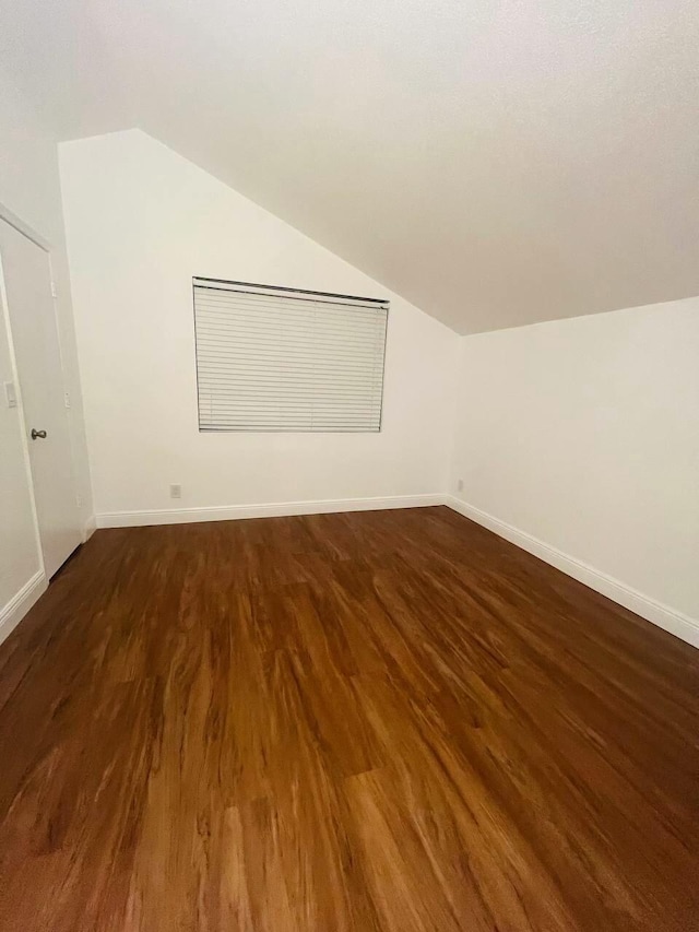 additional living space with baseboards, lofted ceiling, and wood finished floors