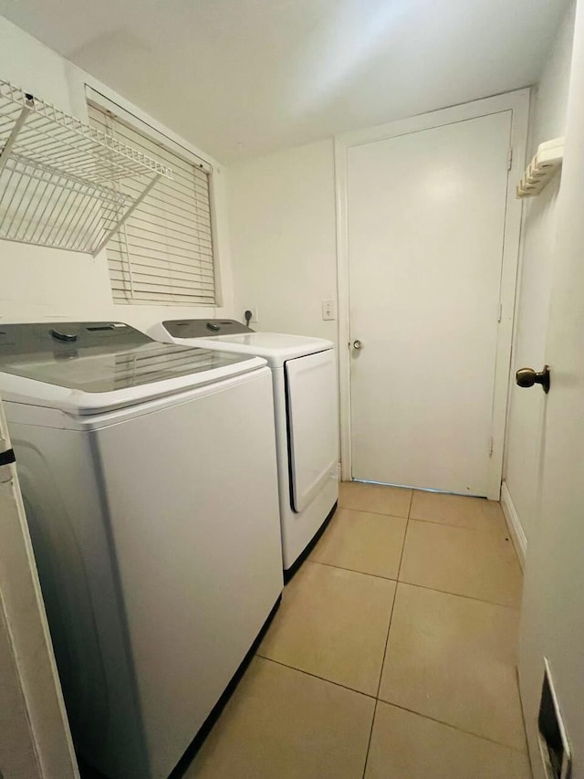 washroom featuring light tile patterned floors, separate washer and dryer, and laundry area