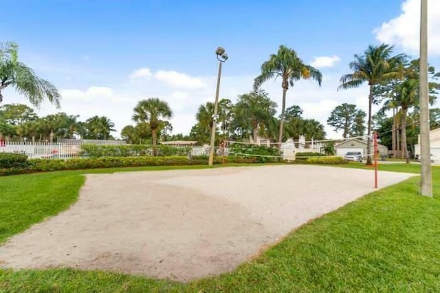 view of property's community with fence, volleyball court, and a lawn