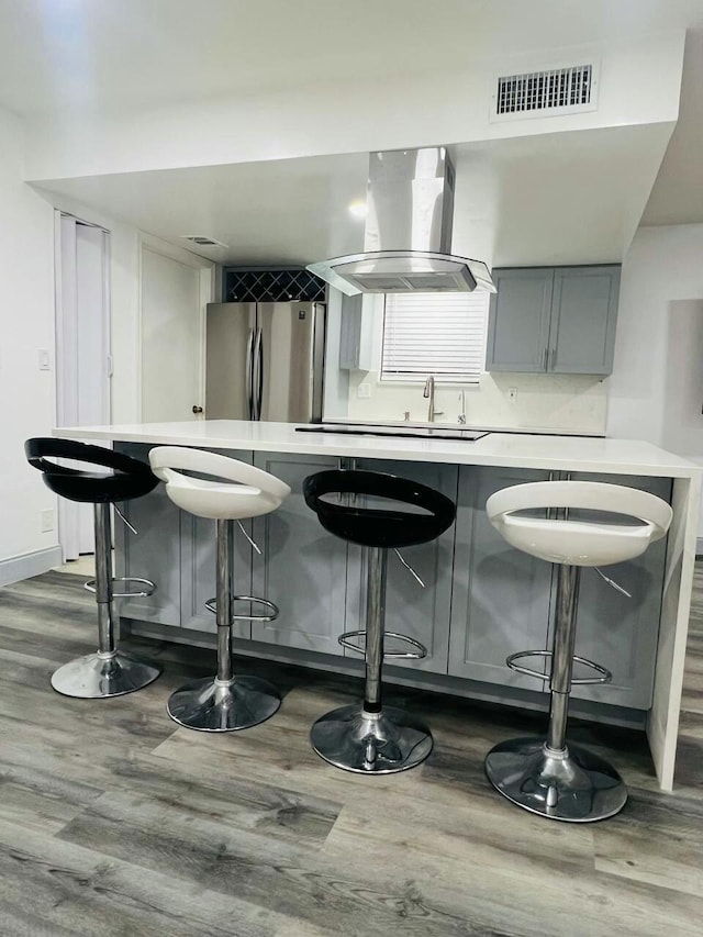 interior space featuring visible vents, freestanding refrigerator, island range hood, light countertops, and dark wood-style flooring