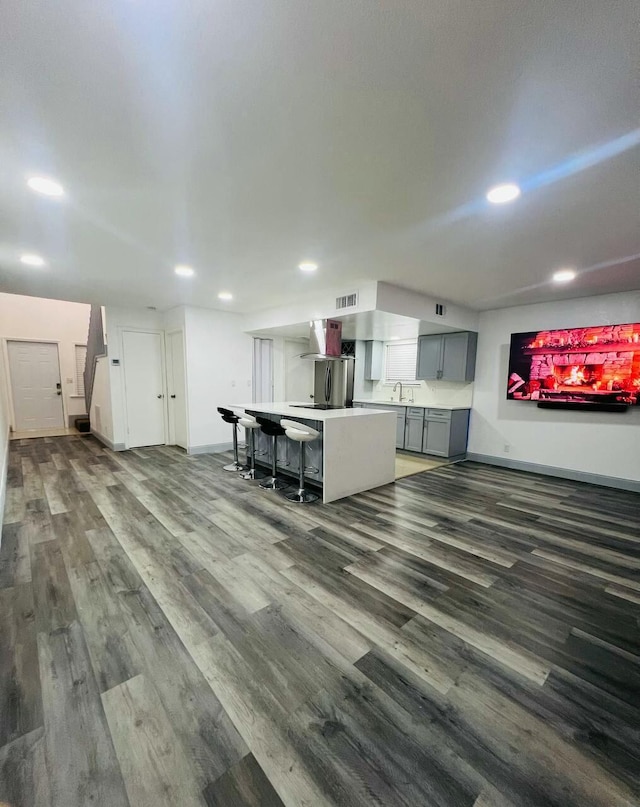 kitchen featuring gray cabinetry, a sink, a kitchen island, wood finished floors, and recessed lighting