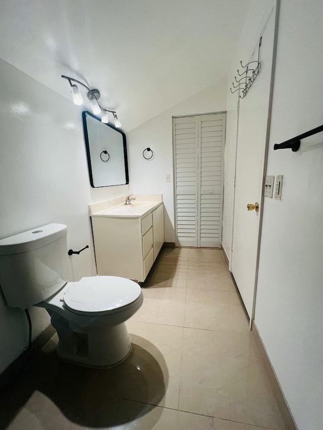 bathroom with baseboards, toilet, vanity, and vaulted ceiling